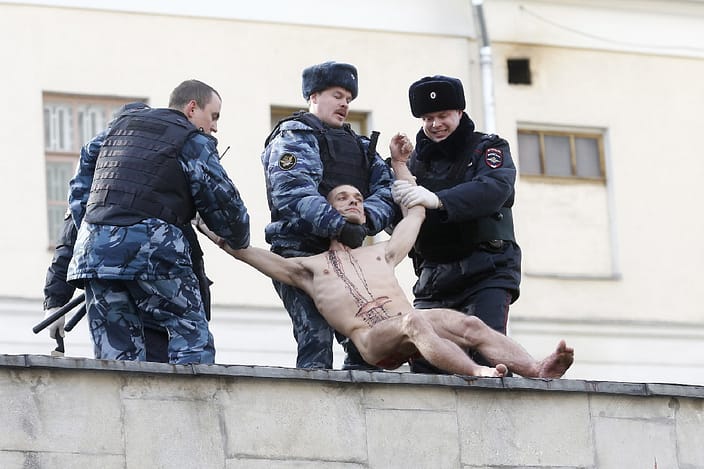 Interior Ministry members detain artist Pyotr Pavlensky after he cut off a part of his earlobe during his protest action titled “Segregation” in Moscow